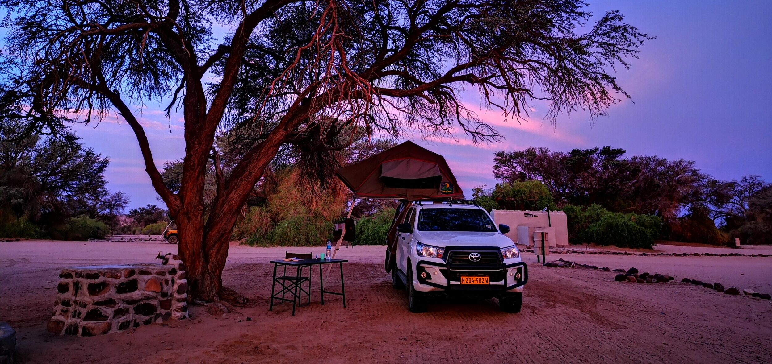 A 4x4 with a rooftop tent at a remote Namibian campsite at dusk