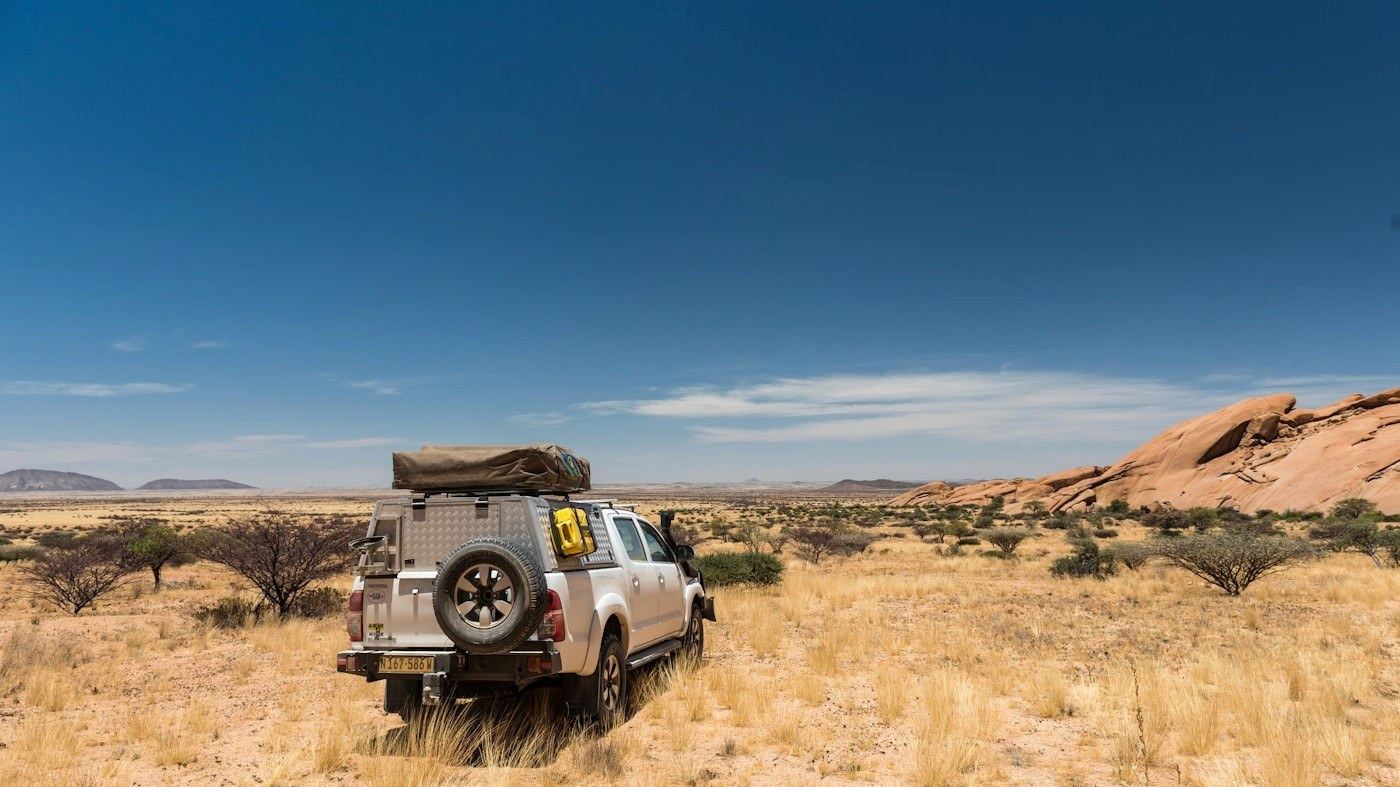 A 4x4 with a rooftop tent at a remote Namibian campsite at dusk